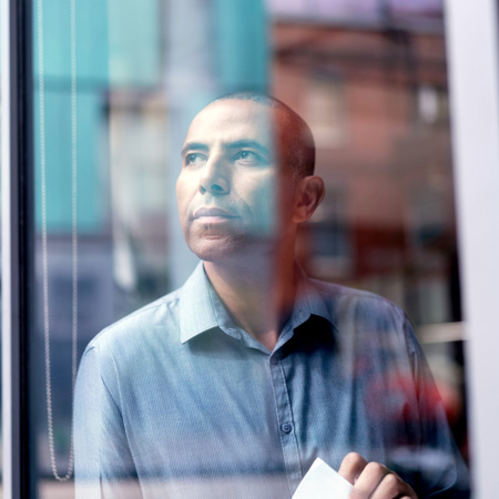 Thoughtful male businessman looking through the glass window