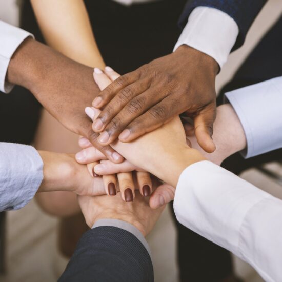 Close up of multiethnic corporate team stacking hands together in office